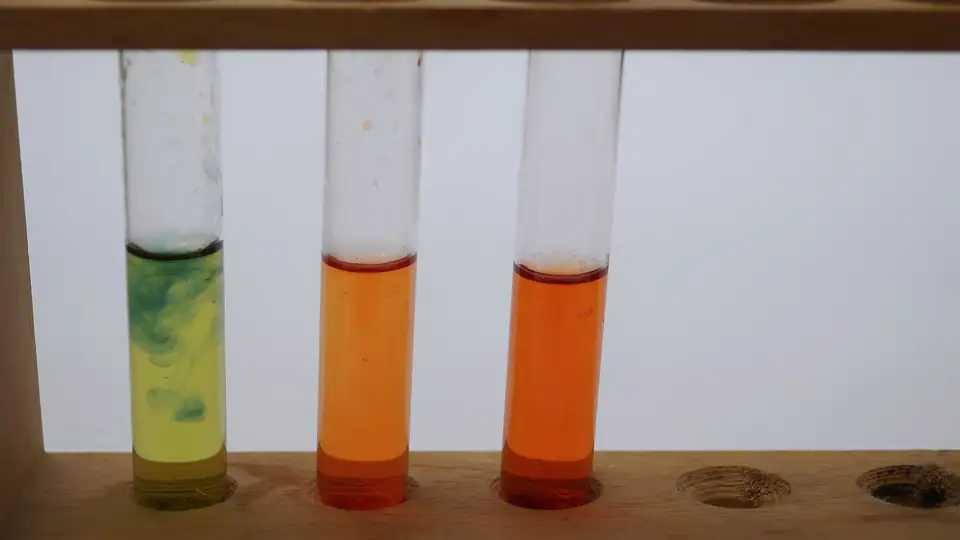 Three test tubes with yellow, orange and green liquids in a rack