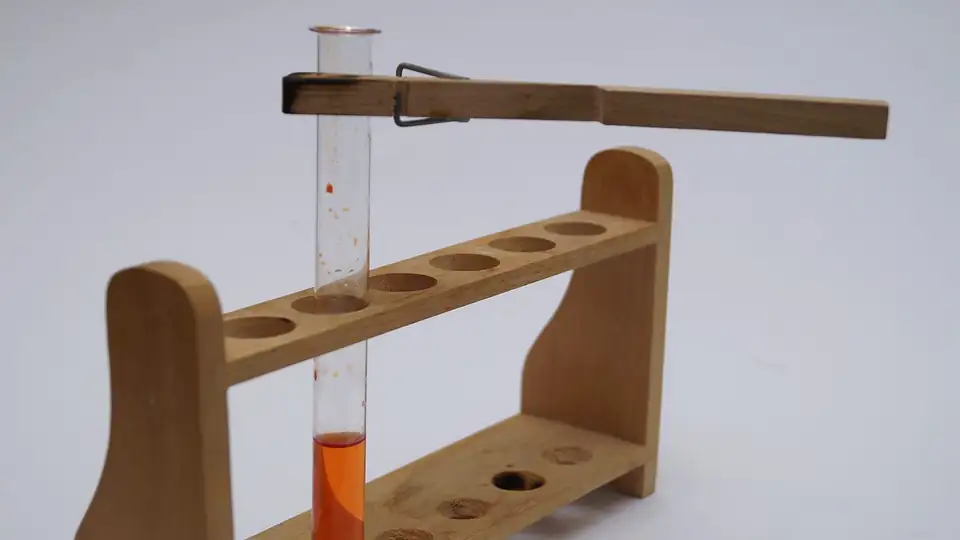 Test tube with orange liquid in a wooden rack
